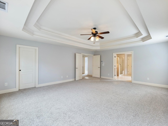 unfurnished bedroom featuring light carpet, visible vents, baseboards, and a tray ceiling