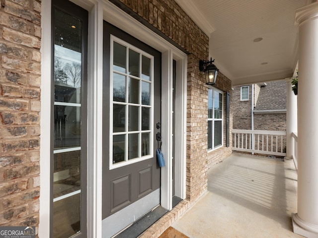 doorway to property featuring brick siding and a porch