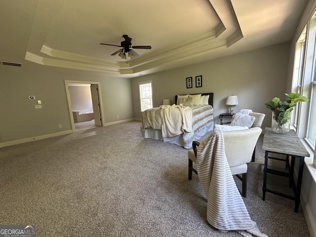 carpeted bedroom featuring a tray ceiling, baseboards, ornamental molding, ceiling fan, and visible vents