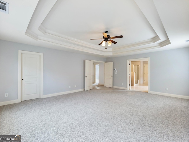 interior space with visible vents, baseboards, a raised ceiling, ceiling fan, and light carpet