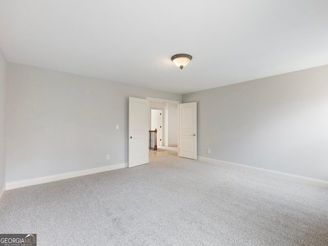 unfurnished room with light colored carpet and baseboards