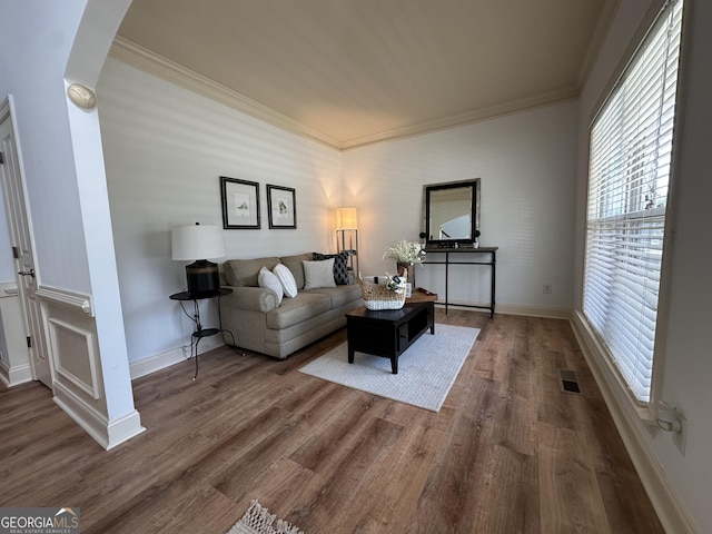 living area featuring plenty of natural light, wood finished floors, and ornamental molding