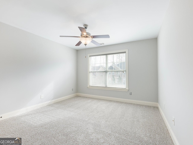 spare room with light colored carpet, baseboards, and a ceiling fan