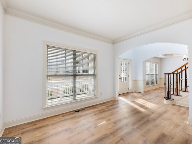 foyer with visible vents, ornamental molding, wood finished floors, arched walkways, and stairs