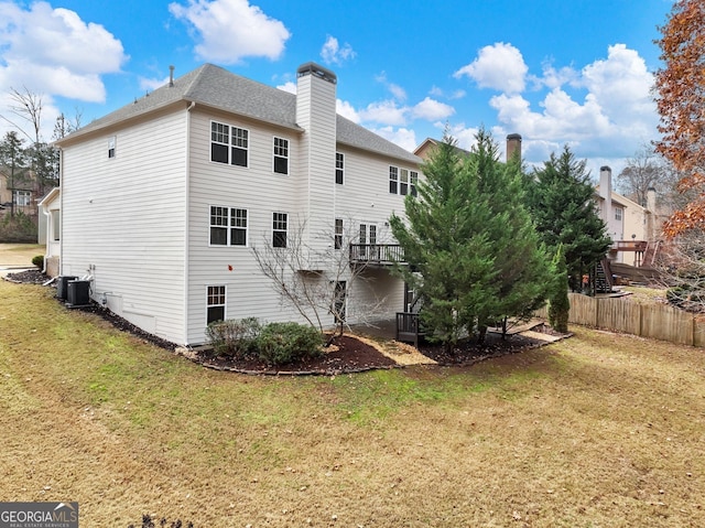 rear view of property featuring a yard, a chimney, fence, central air condition unit, and a shingled roof