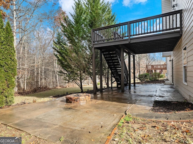 view of patio / terrace with a fire pit, a wooden deck, and stairs