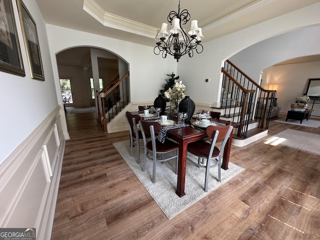 dining area with stairway, arched walkways, a notable chandelier, and wood finished floors