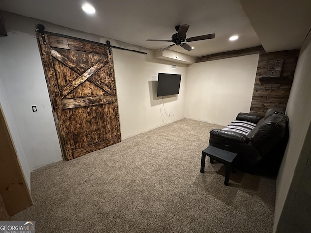 living area featuring a ceiling fan, a barn door, recessed lighting, and carpet