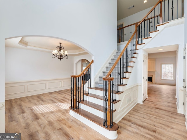 stairway featuring a tray ceiling, wood finished floors, visible vents, and ornamental molding