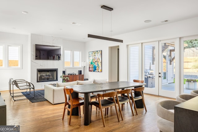 dining room featuring light wood-type flooring, french doors, and visible vents