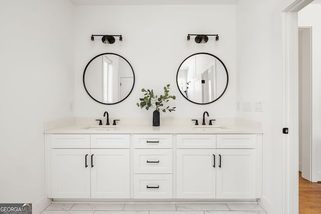 full bathroom with double vanity, baseboards, and a sink