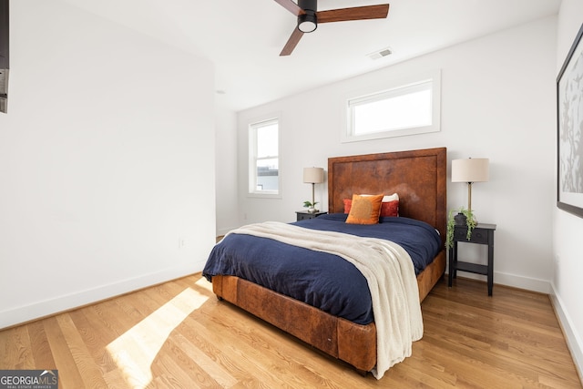 bedroom featuring ceiling fan, wood finished floors, visible vents, and baseboards