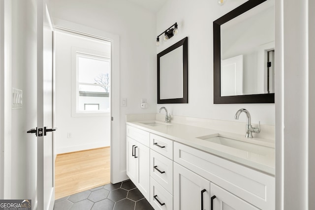 bathroom with a sink, baseboards, double vanity, and tile patterned floors