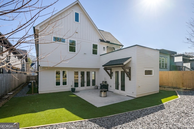 rear view of house featuring a lawn, a fenced backyard, french doors, board and batten siding, and a patio area