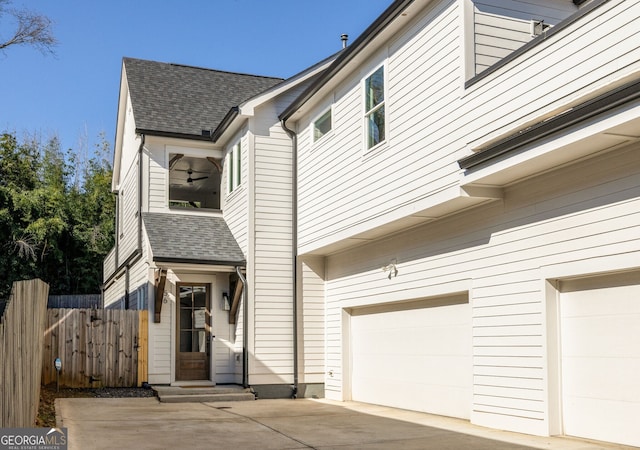 view of property exterior with driveway, a shingled roof, a garage, and fence