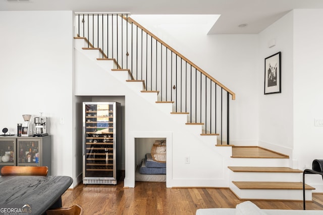 stairs with wine cooler, visible vents, baseboards, and wood finished floors