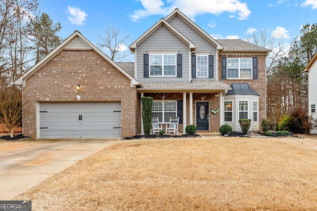 traditional-style house featuring a front lawn, driveway, a porch, an attached garage, and brick siding