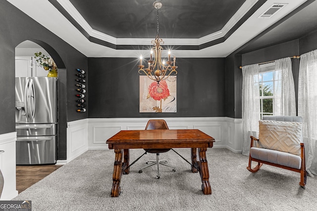 office area featuring visible vents, arched walkways, wainscoting, a raised ceiling, and a notable chandelier