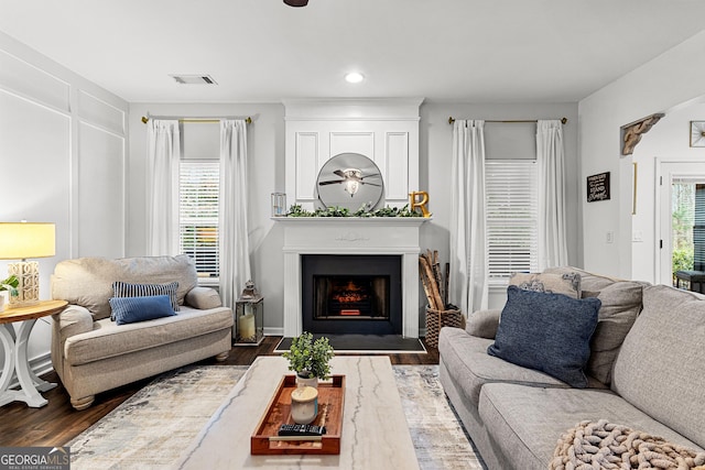 living area with plenty of natural light, wood finished floors, visible vents, and a large fireplace