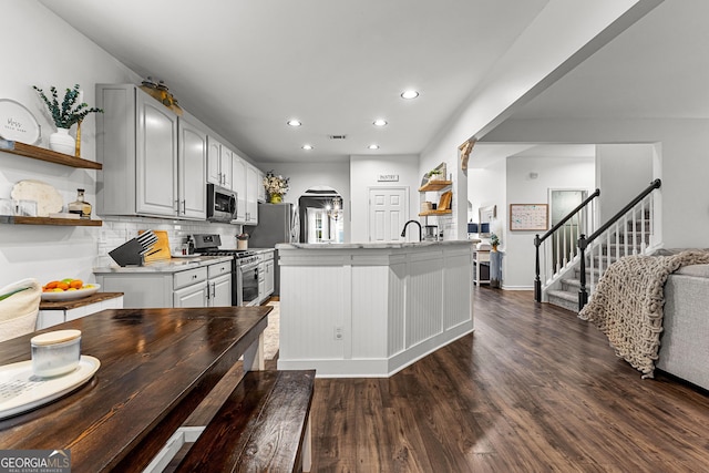 kitchen with light countertops, dark wood-style floors, arched walkways, stainless steel appliances, and open shelves