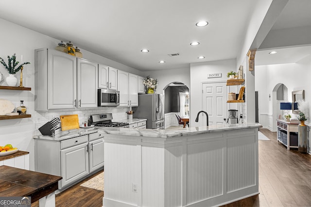 kitchen with open shelves, arched walkways, and stainless steel appliances