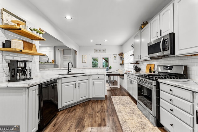 kitchen featuring open shelves, a peninsula, a sink, appliances with stainless steel finishes, and white cabinetry