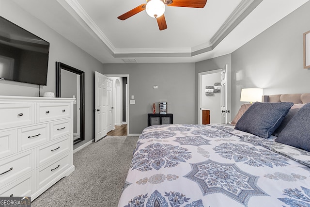 bedroom featuring a raised ceiling, carpet, crown molding, baseboards, and ceiling fan