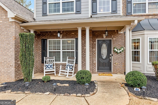 property entrance with brick siding and a porch