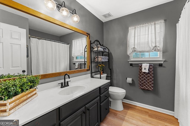 bathroom featuring vanity, wood finished floors, visible vents, baseboards, and toilet