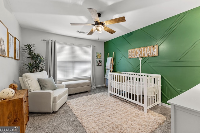 carpeted bedroom featuring a nursery area, a ceiling fan, and visible vents