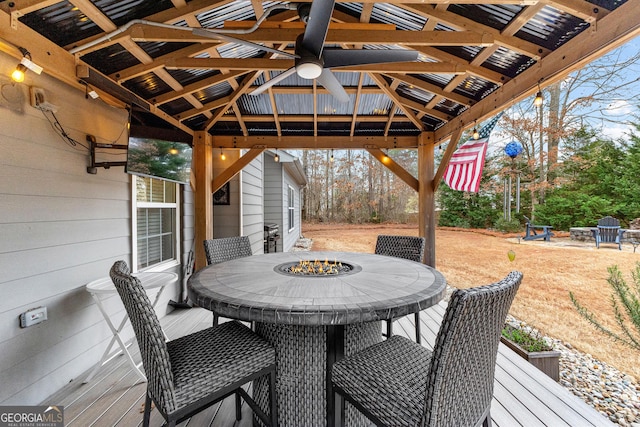 wooden deck with a gazebo, a fire pit, and outdoor dining space