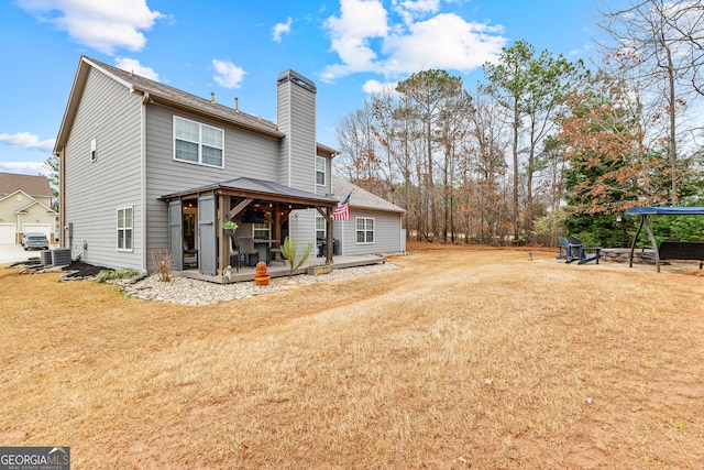 back of property with a gazebo, a deck, a chimney, and a yard