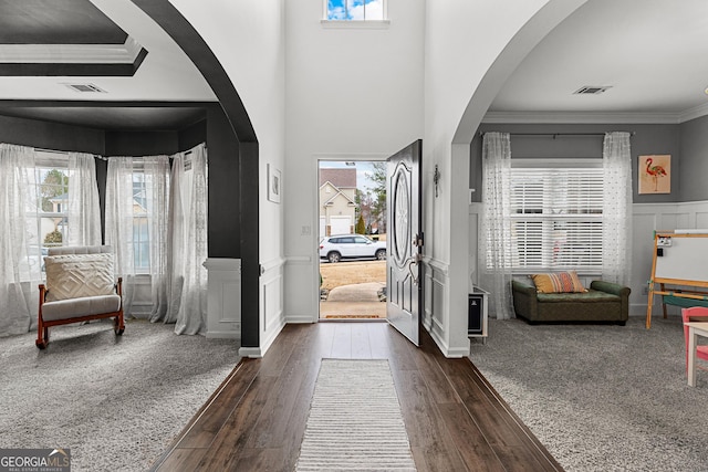 entryway with visible vents, a wainscoted wall, ornamental molding, dark wood-style floors, and arched walkways