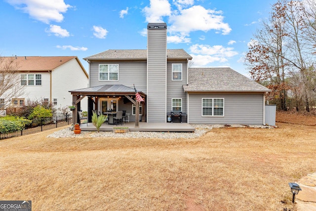 back of property with fence, roof with shingles, a chimney, a gazebo, and a deck