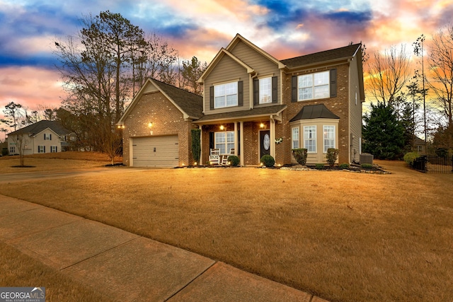 traditional-style home with central AC unit, a front lawn, concrete driveway, a garage, and brick siding