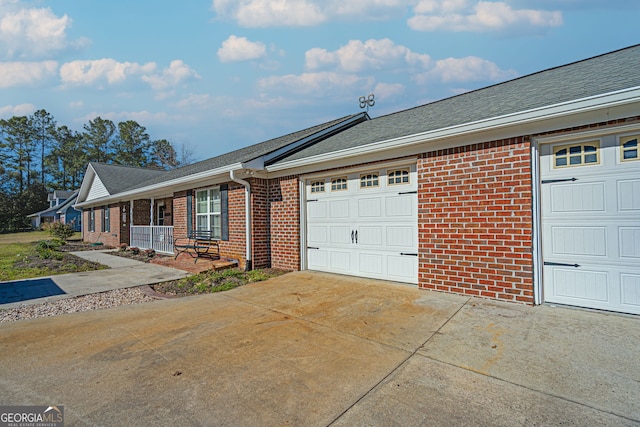 view of front of home with brick siding, covered porch, driveway, and a garage