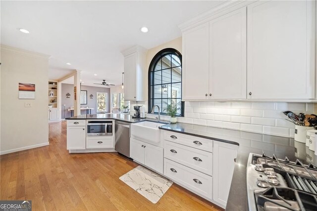 217 Colonial Dr, Woodstock, GA 30189 - kitchen featuring appliances with stainless steel finishes, a peninsula, decorative backsplash, dark countertops, and a sink