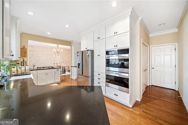 217 Colonial Dr, Woodstock, GA 30189 - kitchen featuring stainless steel appliances, dark countertops, a chandelier, white cabinetry, and ornamental molding