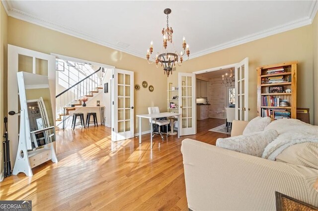 217 Colonial Dr, Woodstock, GA 30189 - living room featuring french doors, a chandelier, ornamental molding, stairs, and light wood-style flooring