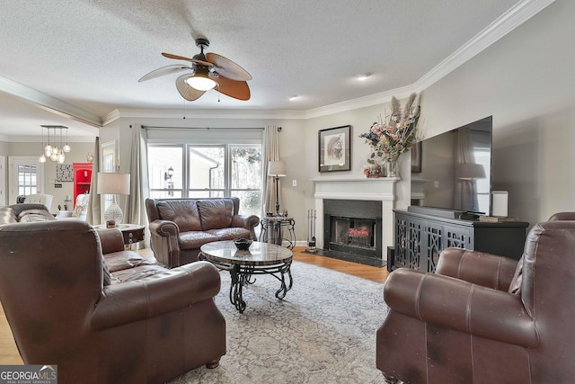 living area with wood finished floors, a fireplace with flush hearth, ceiling fan, a textured ceiling, and crown molding