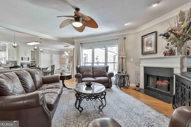 living area featuring a fireplace with flush hearth, a textured ceiling, wood finished floors, and ornamental molding