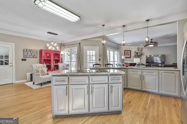 kitchen with light wood-type flooring, ornamental molding, gray cabinets, decorative light fixtures, and open floor plan