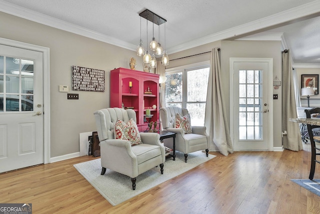 sitting room featuring baseboards, light wood-style floors, ornamental molding, and a textured ceiling