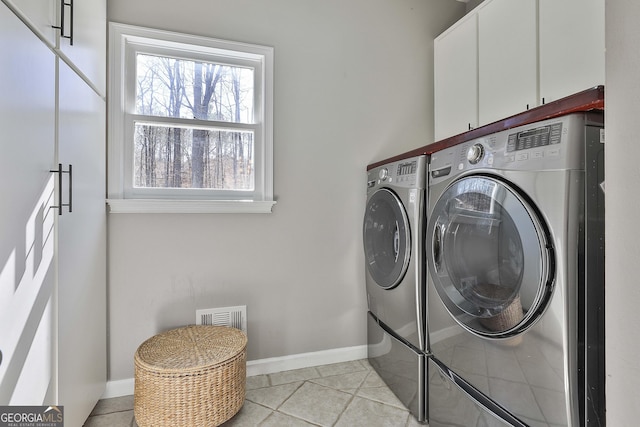 washroom featuring washing machine and clothes dryer, visible vents, baseboards, light tile patterned floors, and cabinet space