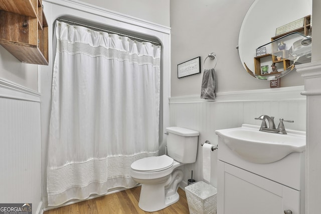 full bathroom featuring vanity, toilet, wood finished floors, and a wainscoted wall