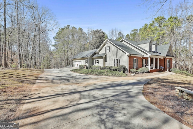 view of home's exterior featuring concrete driveway, a garage, covered porch, and brick siding