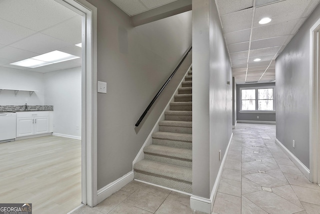 stairs featuring baseboards and a paneled ceiling