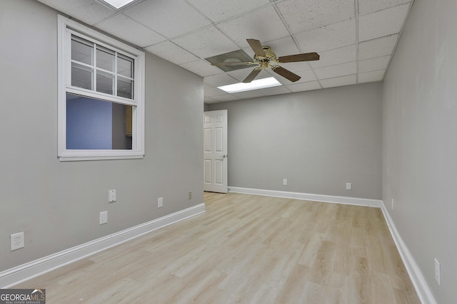 spare room featuring a paneled ceiling, baseboards, wood finished floors, and a ceiling fan