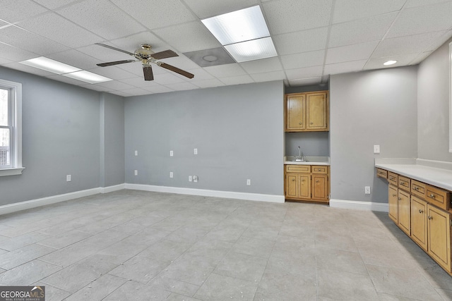 kitchen featuring brown cabinets, light countertops, baseboards, and a sink