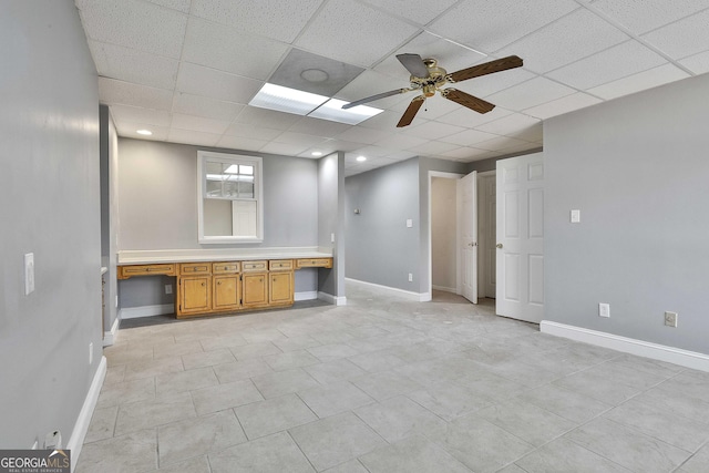 interior space with a drop ceiling, baseboards, and built in study area